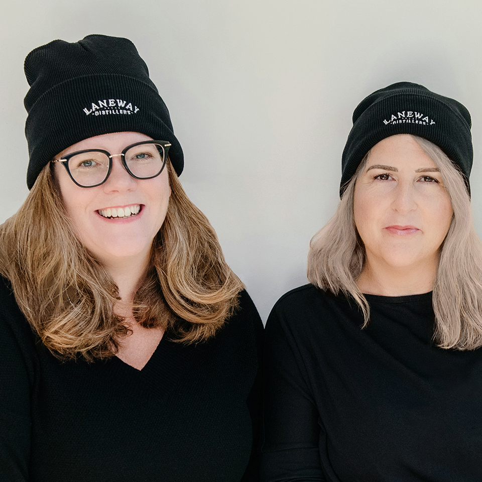 Two women, Jessica Chester and Reagan Soucie, wearing matching black sweatshirts and toques