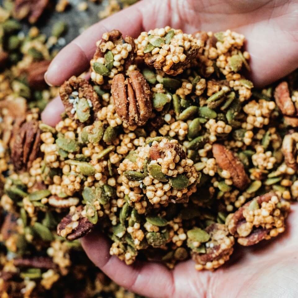 A person's hands scooping up granola with nuts