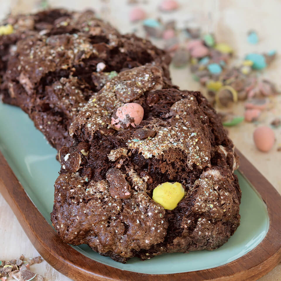 A plate with chocolate Mini Egg scones and crushed Mini Eggs visible in the background