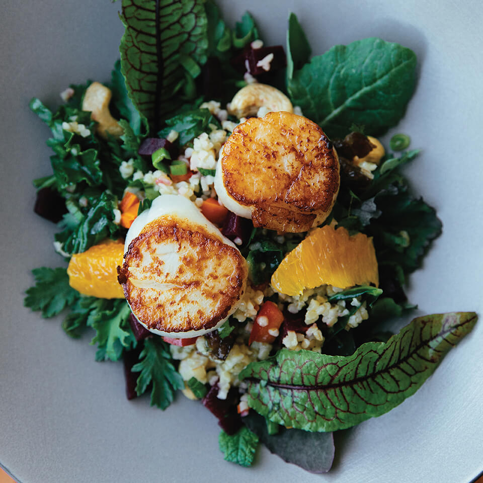 A salad topped with seared scallops
