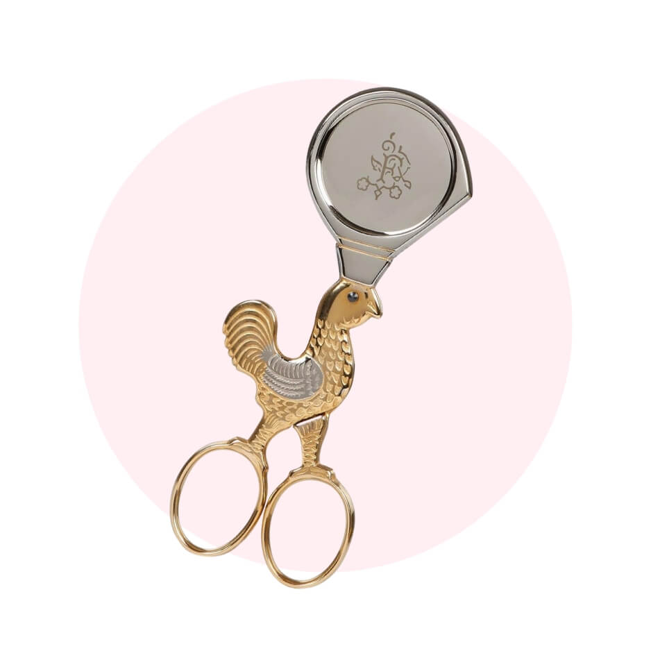 A pair of embroidery scissors over a light pink circle