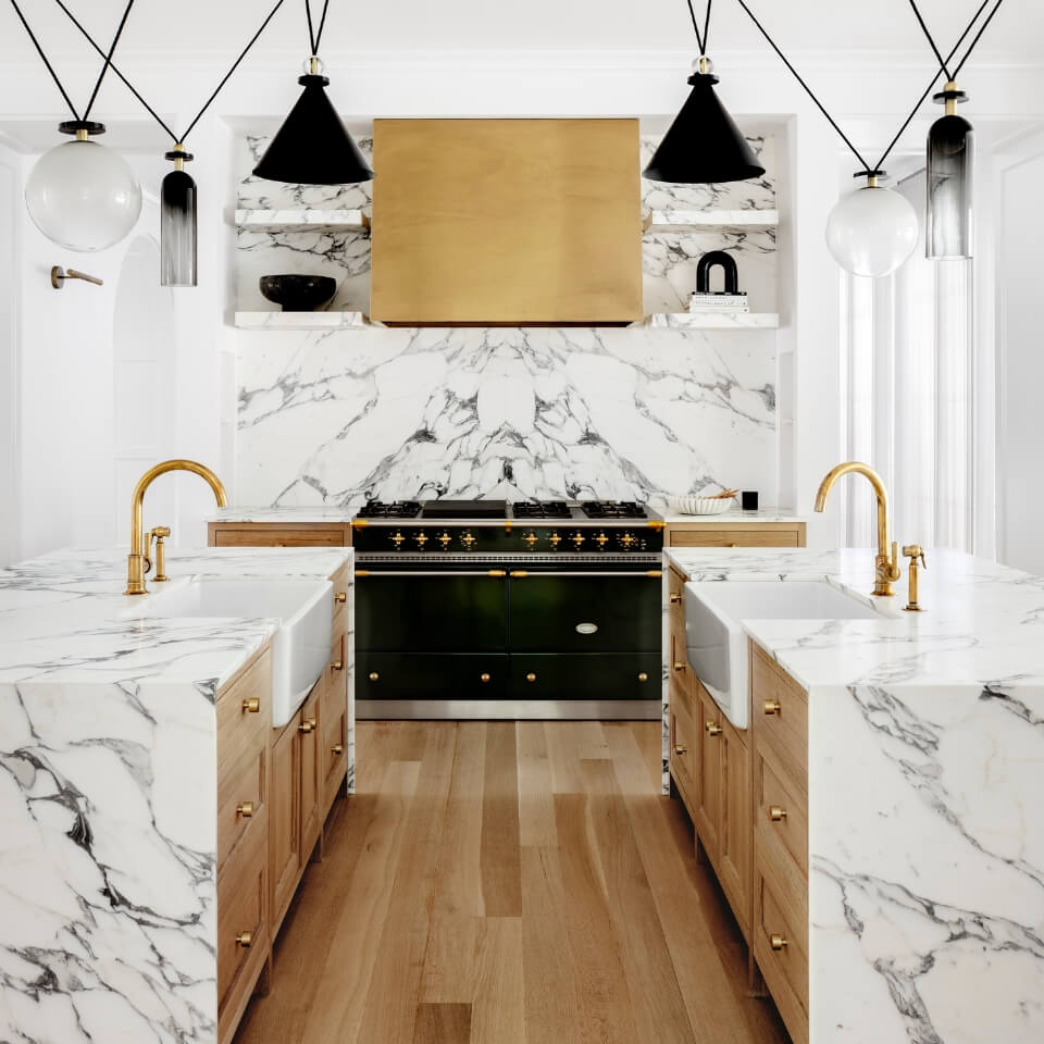 A view of a kitchen in white marble and wood tones