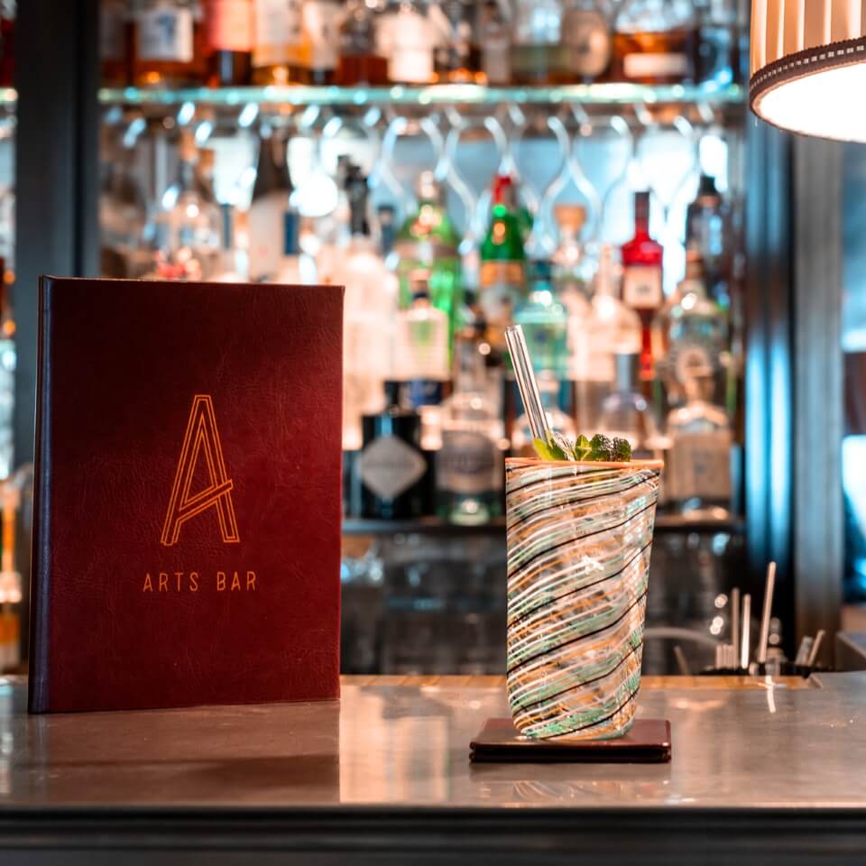 A drink on a bar surface with a red menu with an A on it next to it