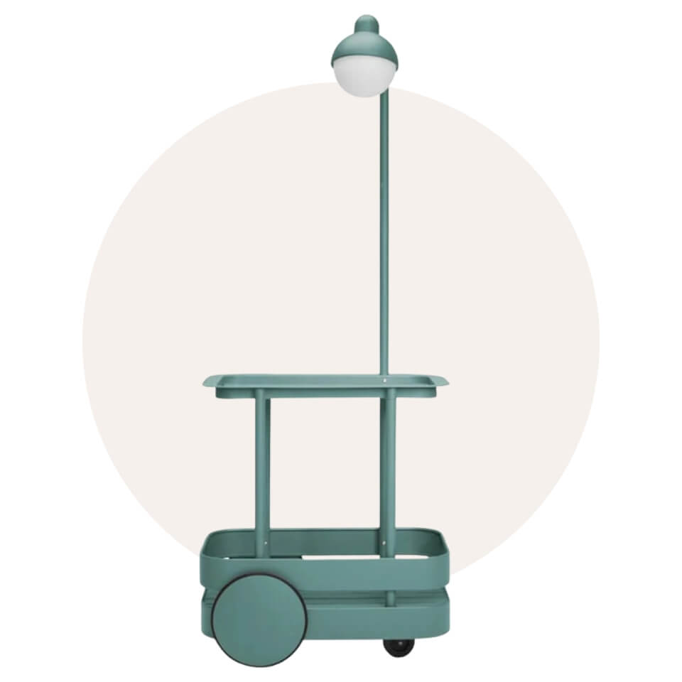 A turquoise wheeled cart with a lamp over a cream-coloured circle