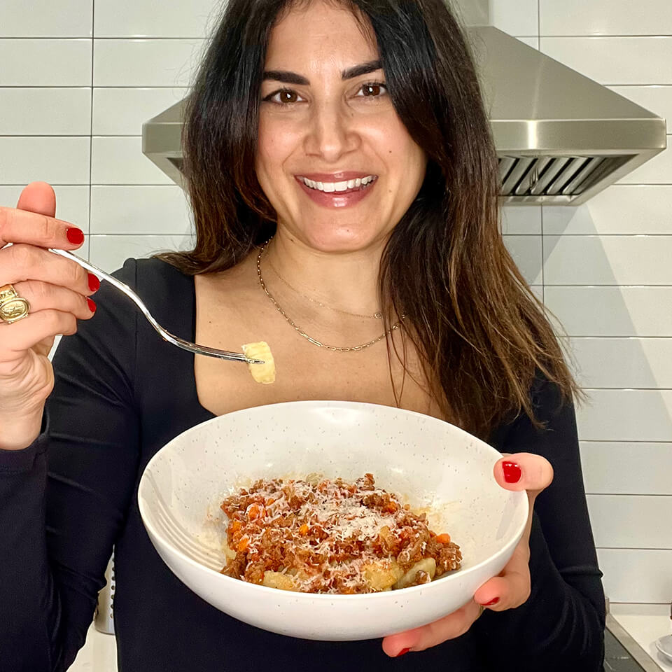 A woman holding up a piece of gnocchi with a fork