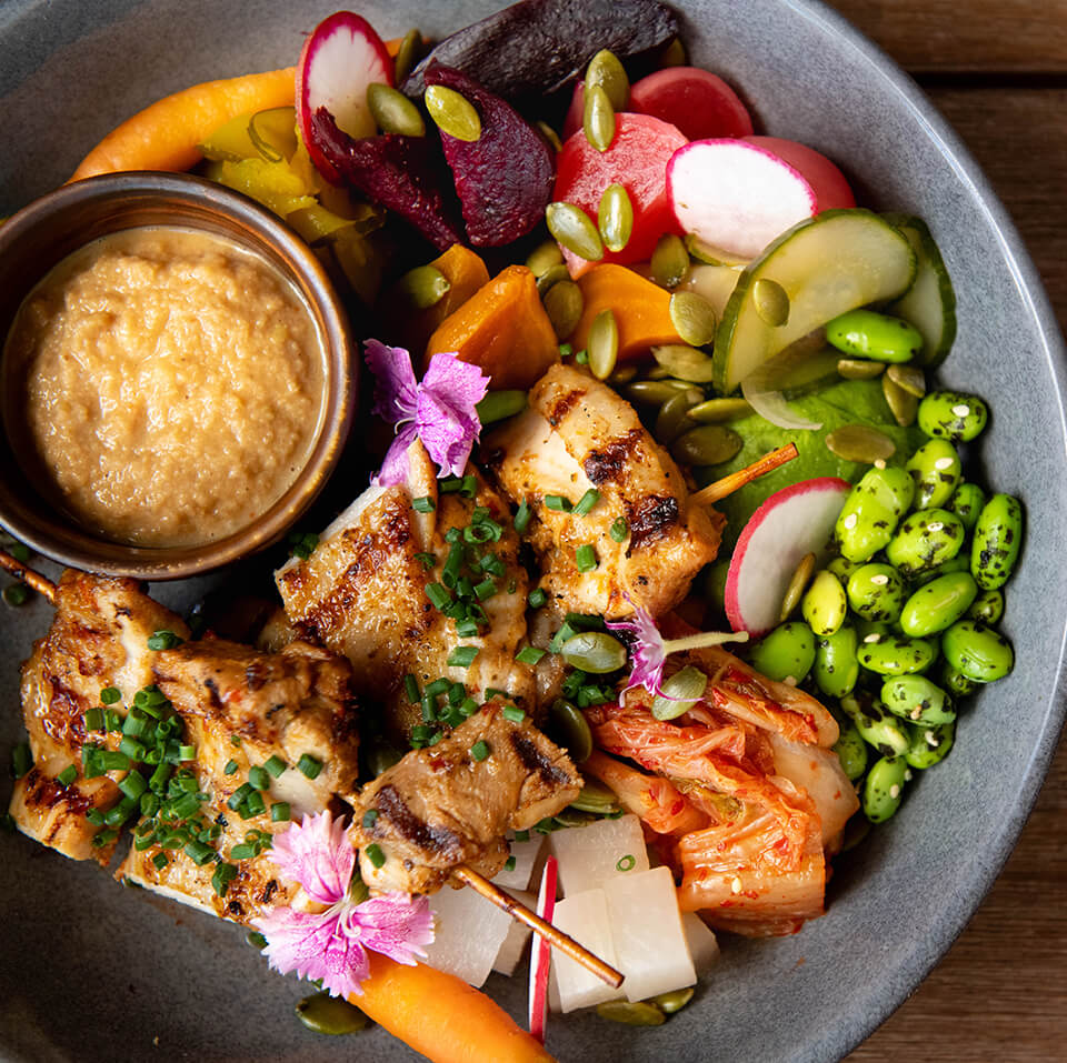 A bowl filled with various healthy fillings and a small dish of sauce