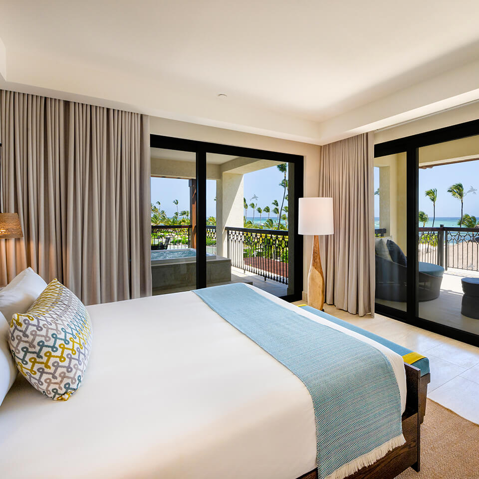 A bedroom overlooking a beach with palm trees