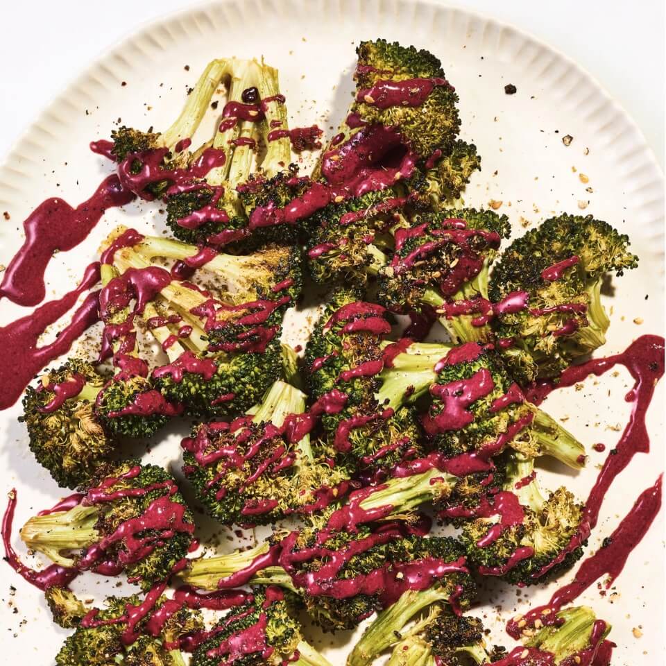 A dish of roasted broccoli drizzled with red tahini