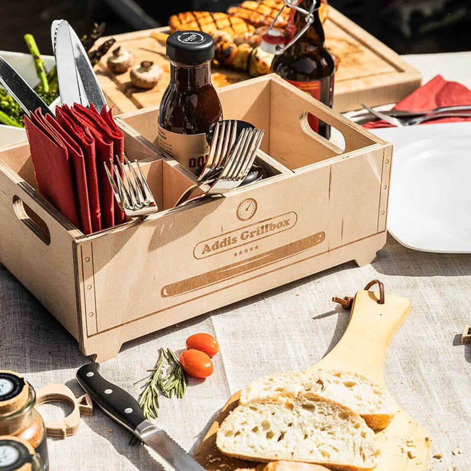 A wooden box with grilling equipment and cutlery