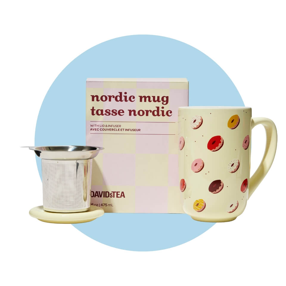 A light yellow mug with a donut pattern, box and lid with strainer over a light blue circle