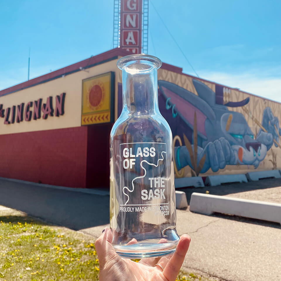 A person holding up a clear bottle in front of a building