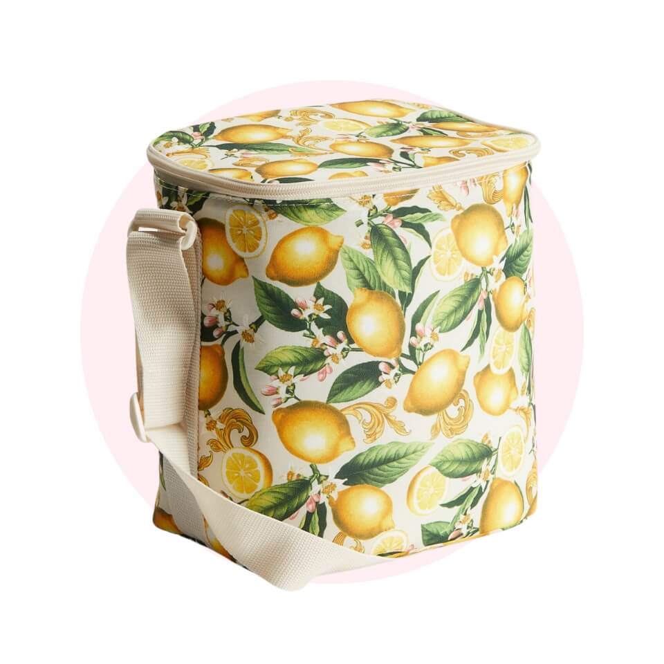 A cooler bag with a lemon pattern over a light pink circle