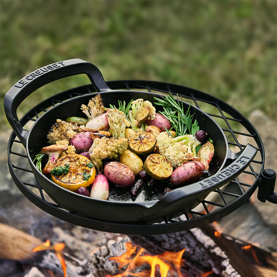A cast iron pan with food over a campfire