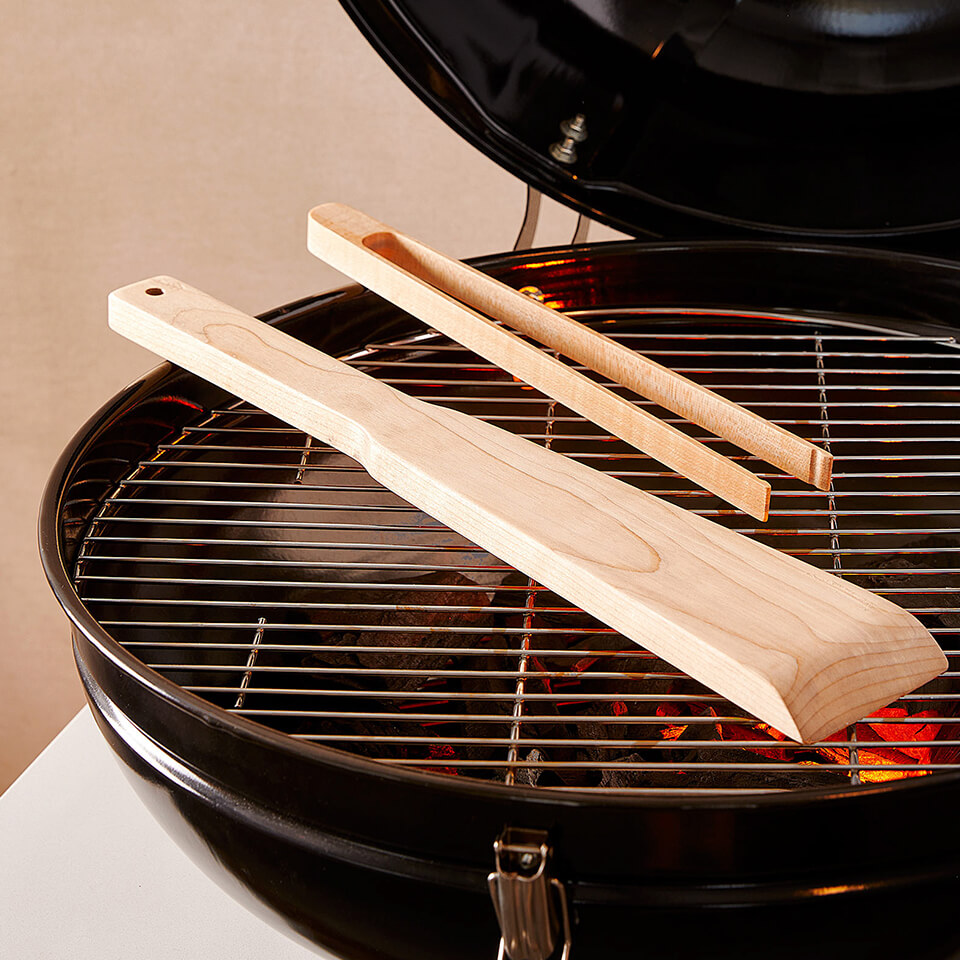 Two wooden grilling tools on a grill