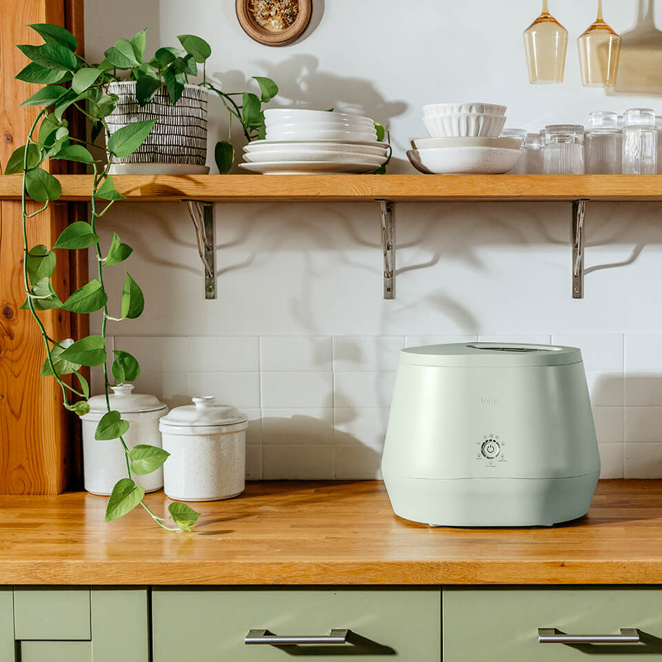A light green Lomi composter on a countertop