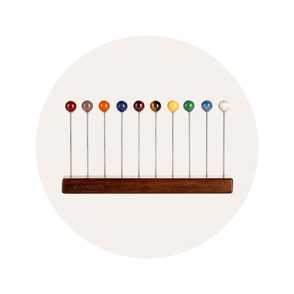 Cocktail picks with coloured heads in a wooden stand inside a cream-coloured circle