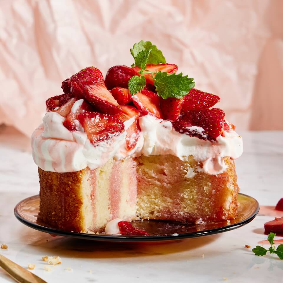 A cake topped with frosting and sliced strawberries on a plate