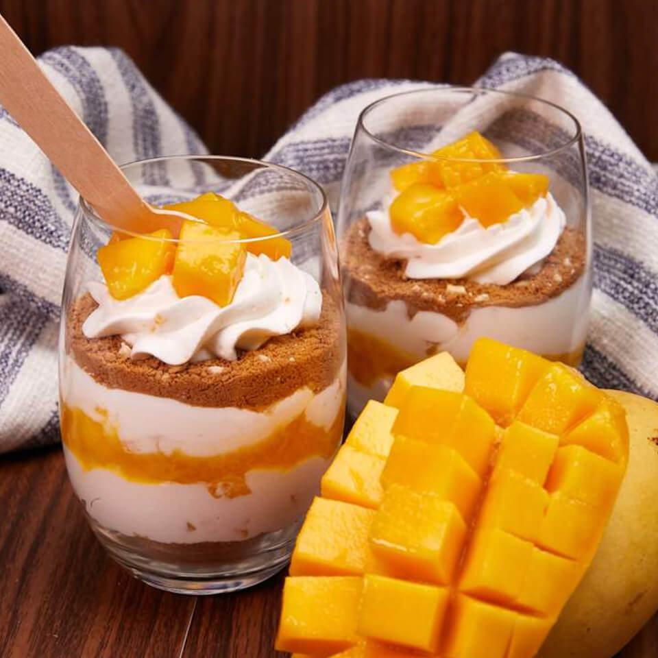 Serving a mango float in a stemless wine glass makes it instantly look like a tiramisu. This easy mango float recipe has three layers of whipped cream with small mango chunks on top.