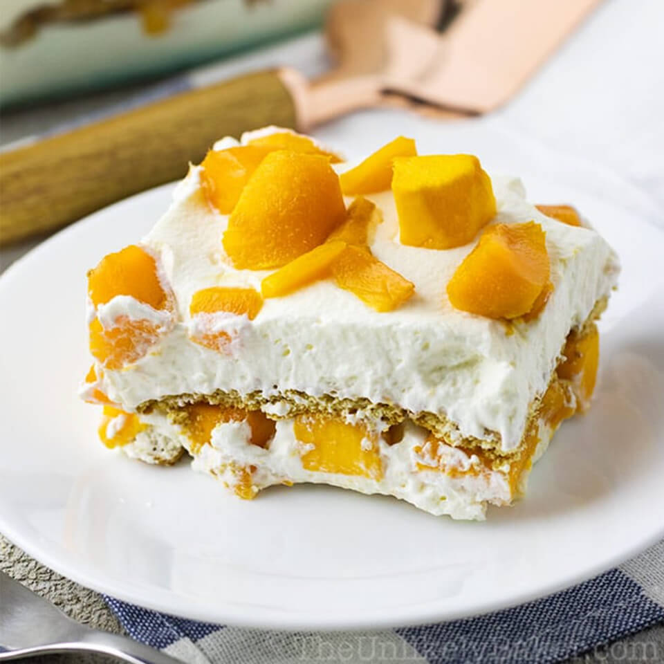 A close up image of a two-layered Mango Float recipe with lots of whipped cream.