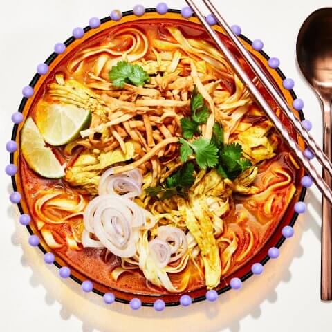A dish of khao soi with chopsticks and a spoon