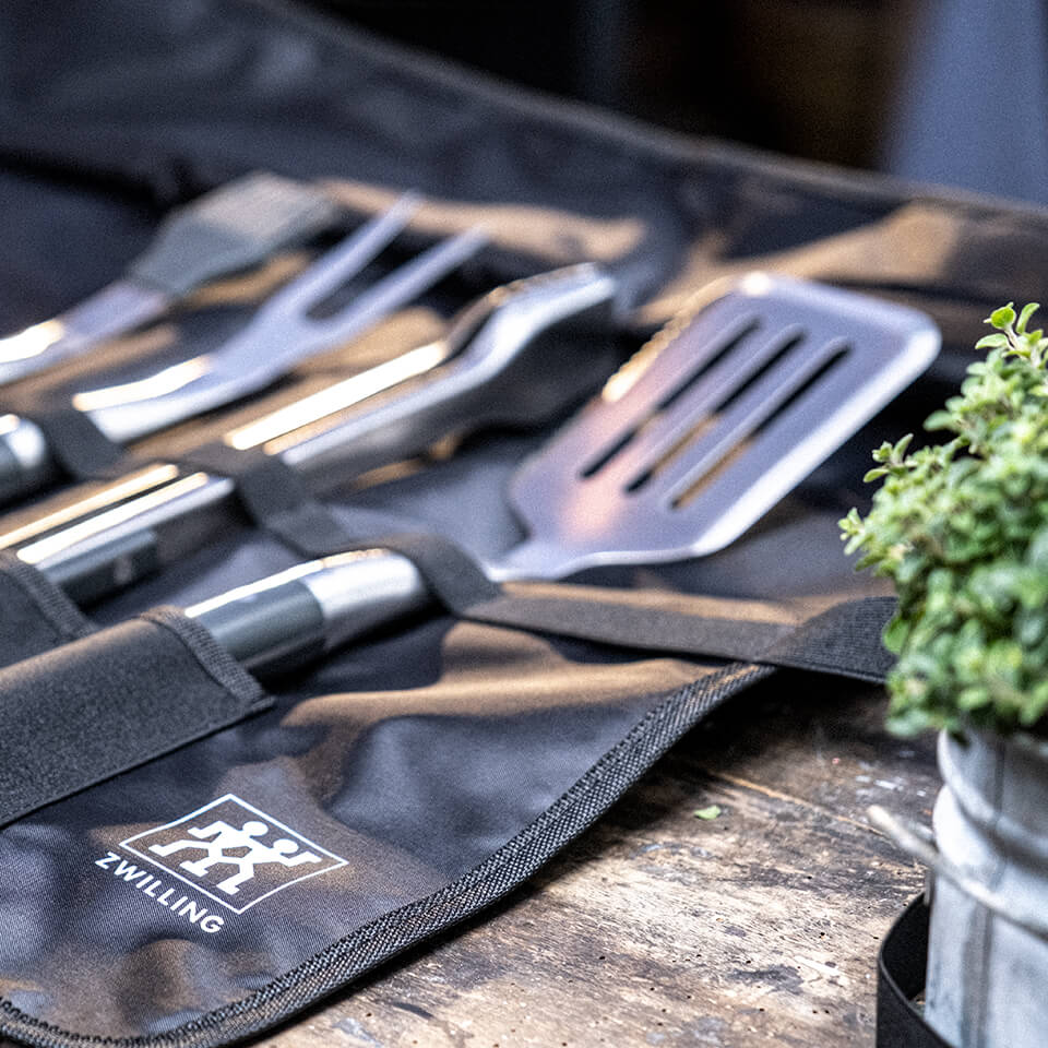 A black wrap with four silver grilling tools
