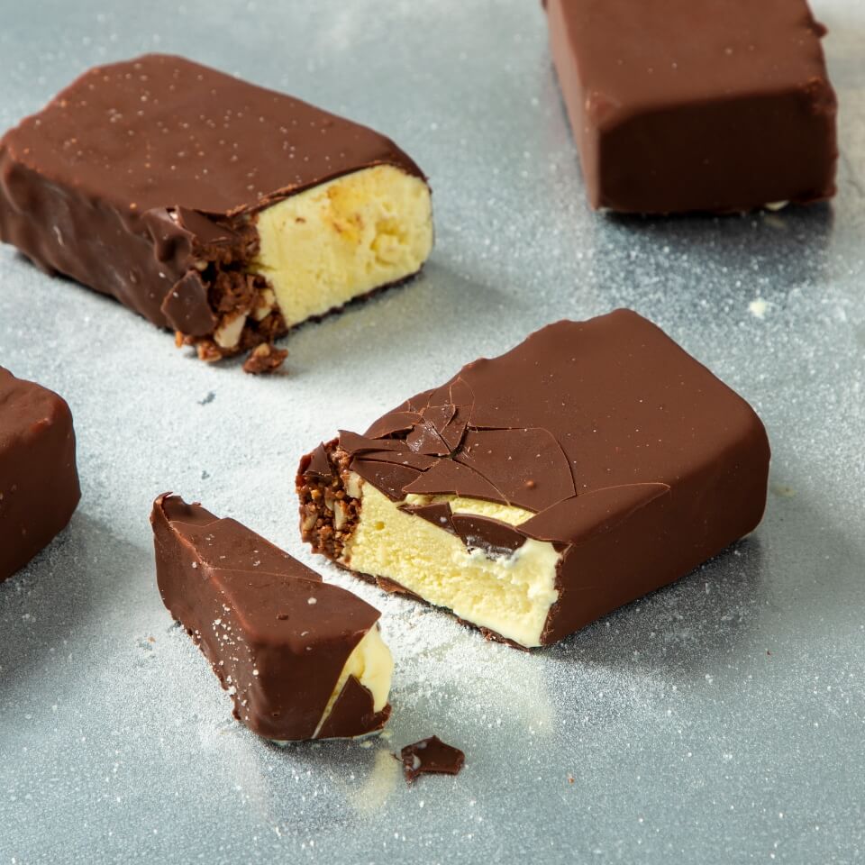 Chocolate-covered bars of yellow ice cream on a steel-coloured surface