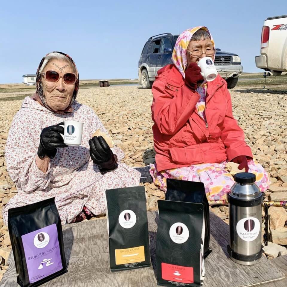 Two women drinking coffee outside