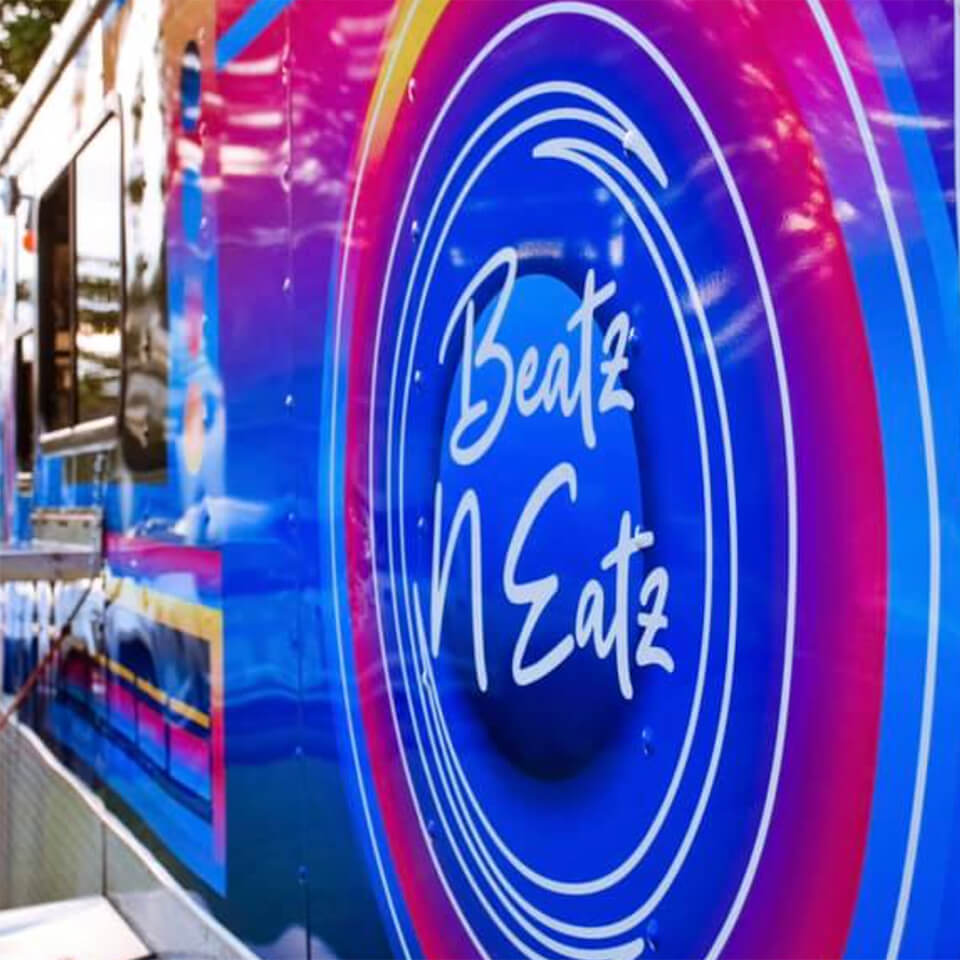The side of a food truck decorated to look like a neon beat box