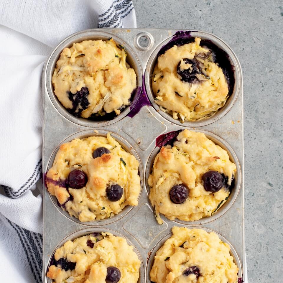 A silver muffin tin with blueberry muffins