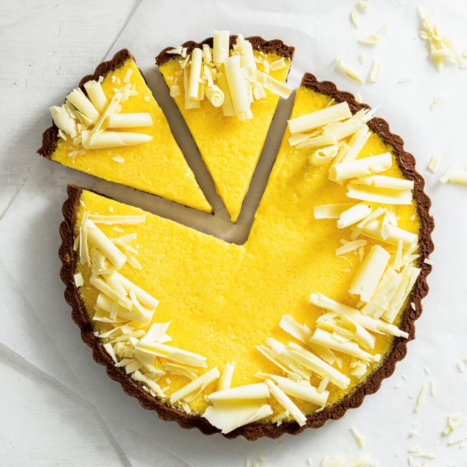 A yellow and dark chocolate tart on a marble surface