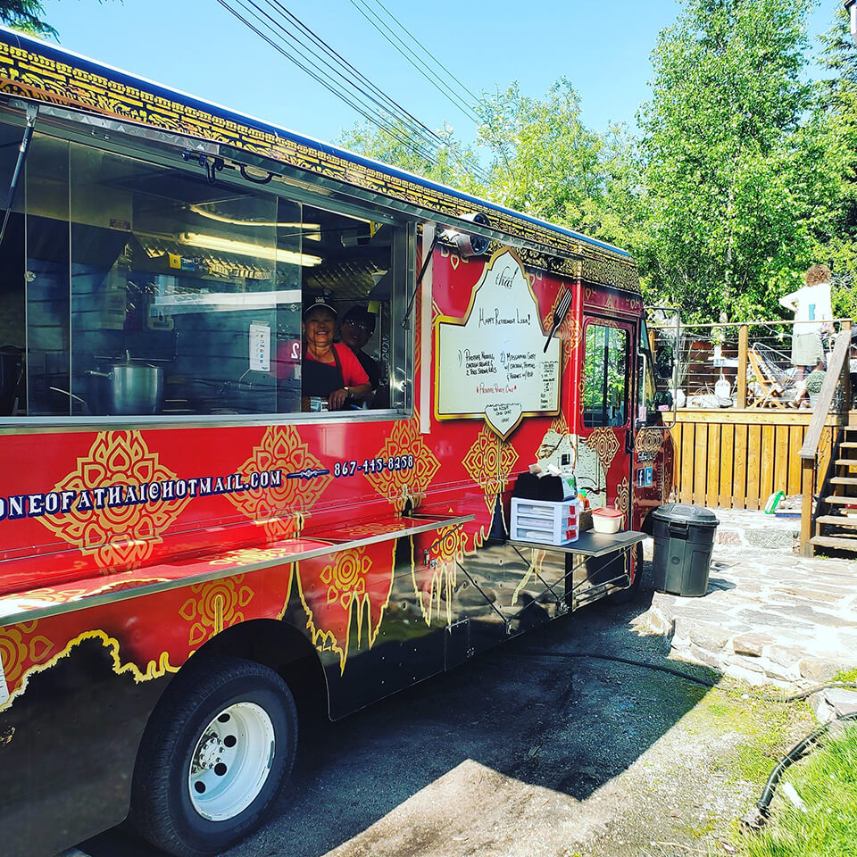 A red and gold food truck with a person smiling in the window
