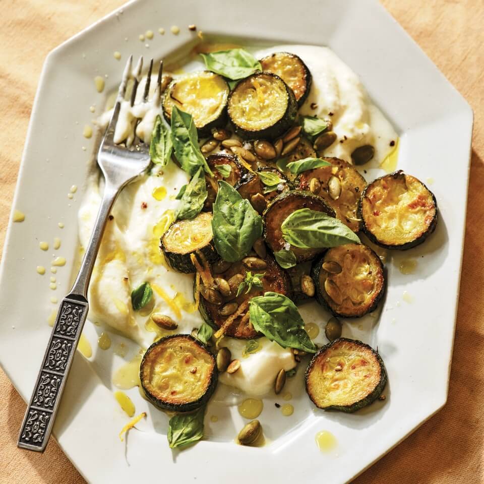 A white plate with roasted zucchini, labneh and a fork