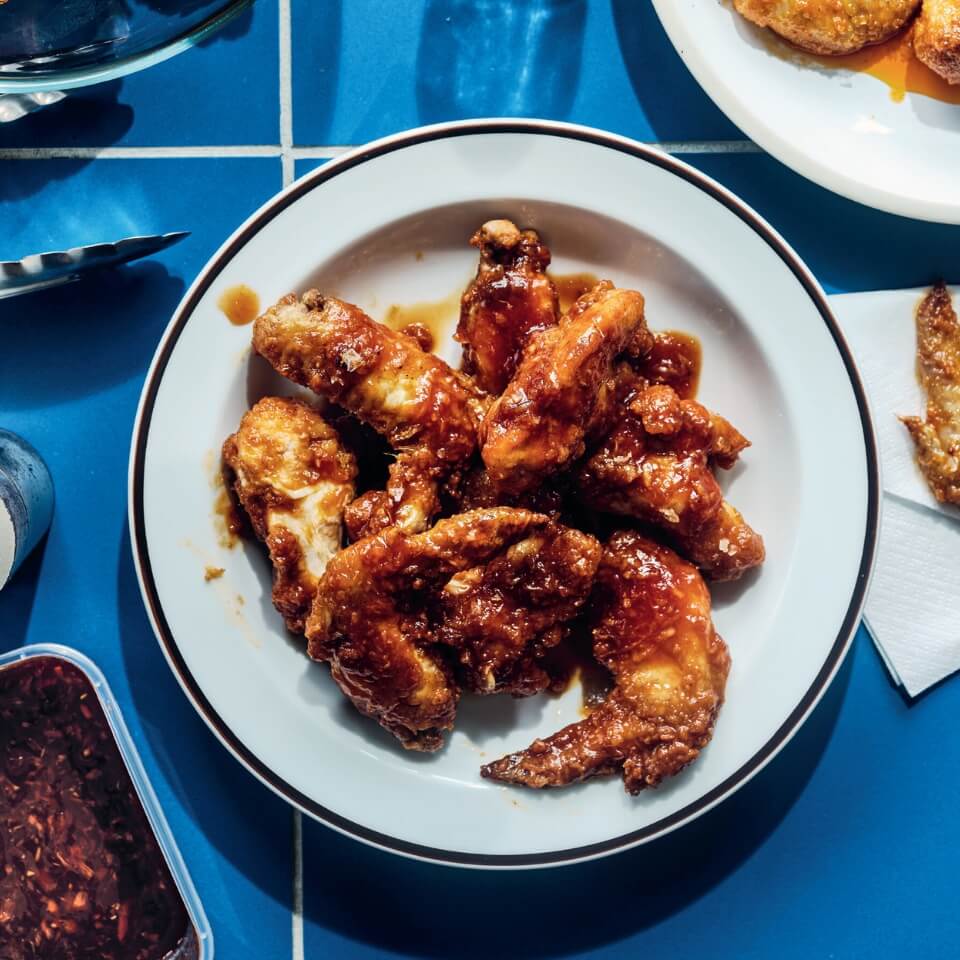 A dish with chicken wings on a blue tabletop