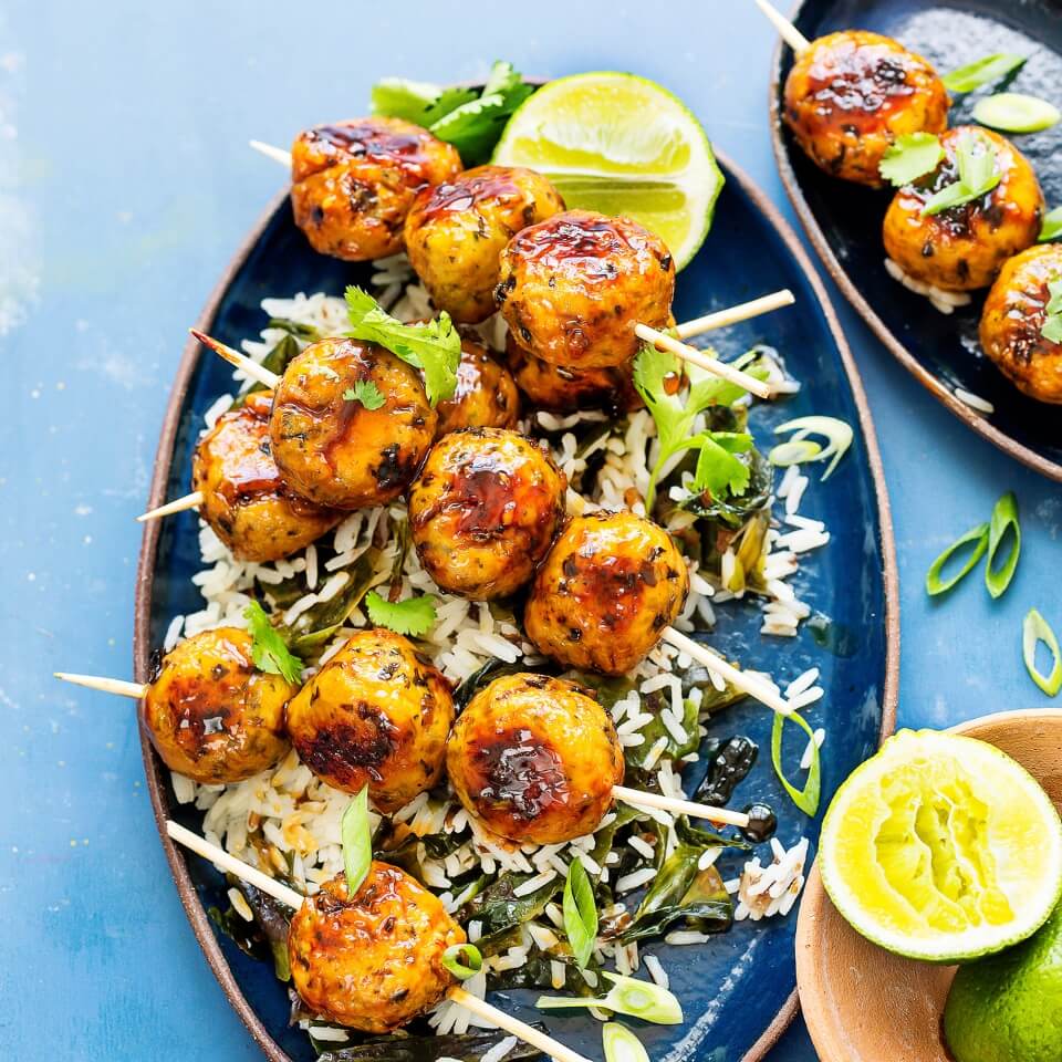 A blue oval-shaped platter with chicken meatball skewers