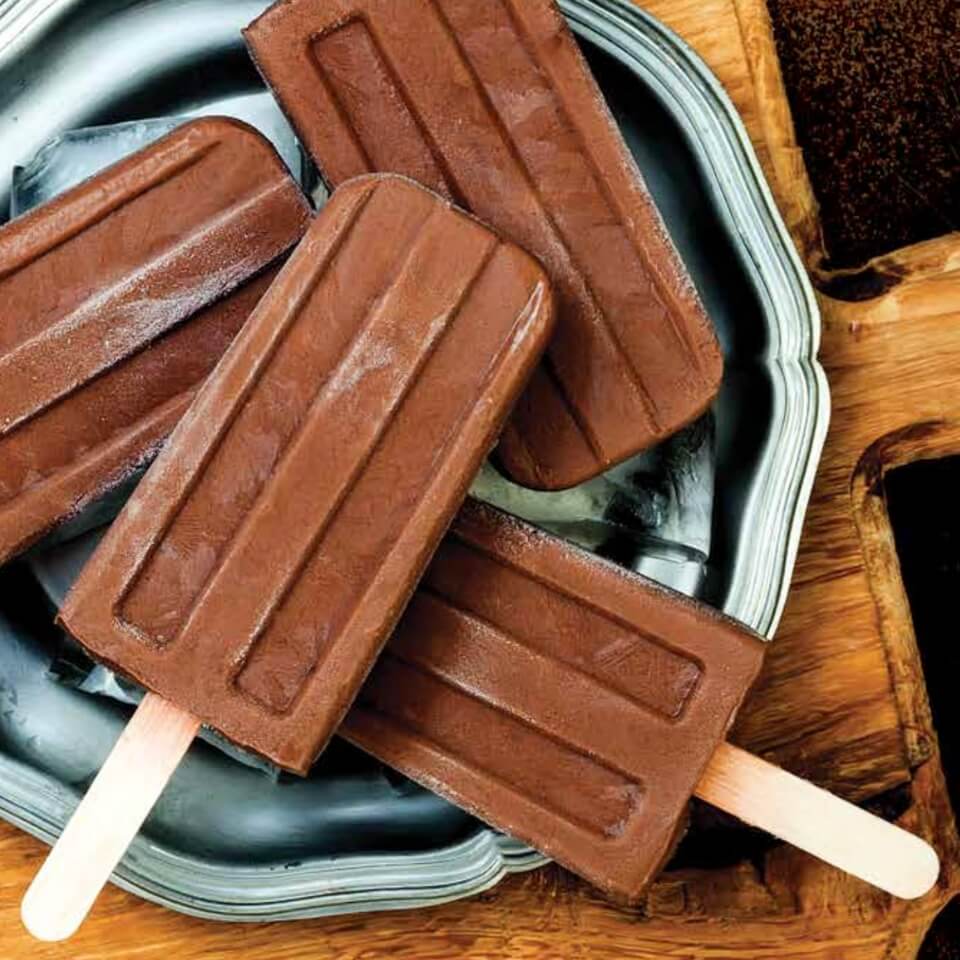 A blue plate with chocolate popsicles on a wooden table