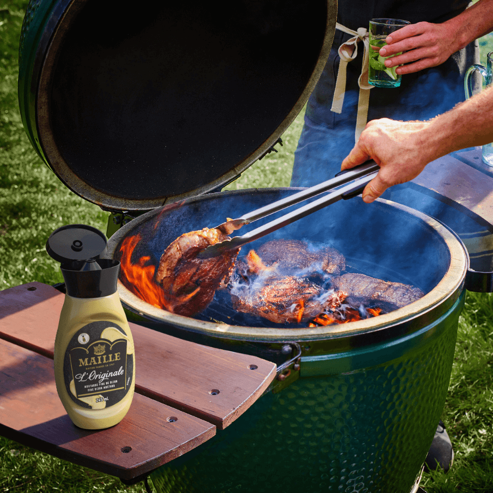 person cooking chicken on green egg smoker bbq