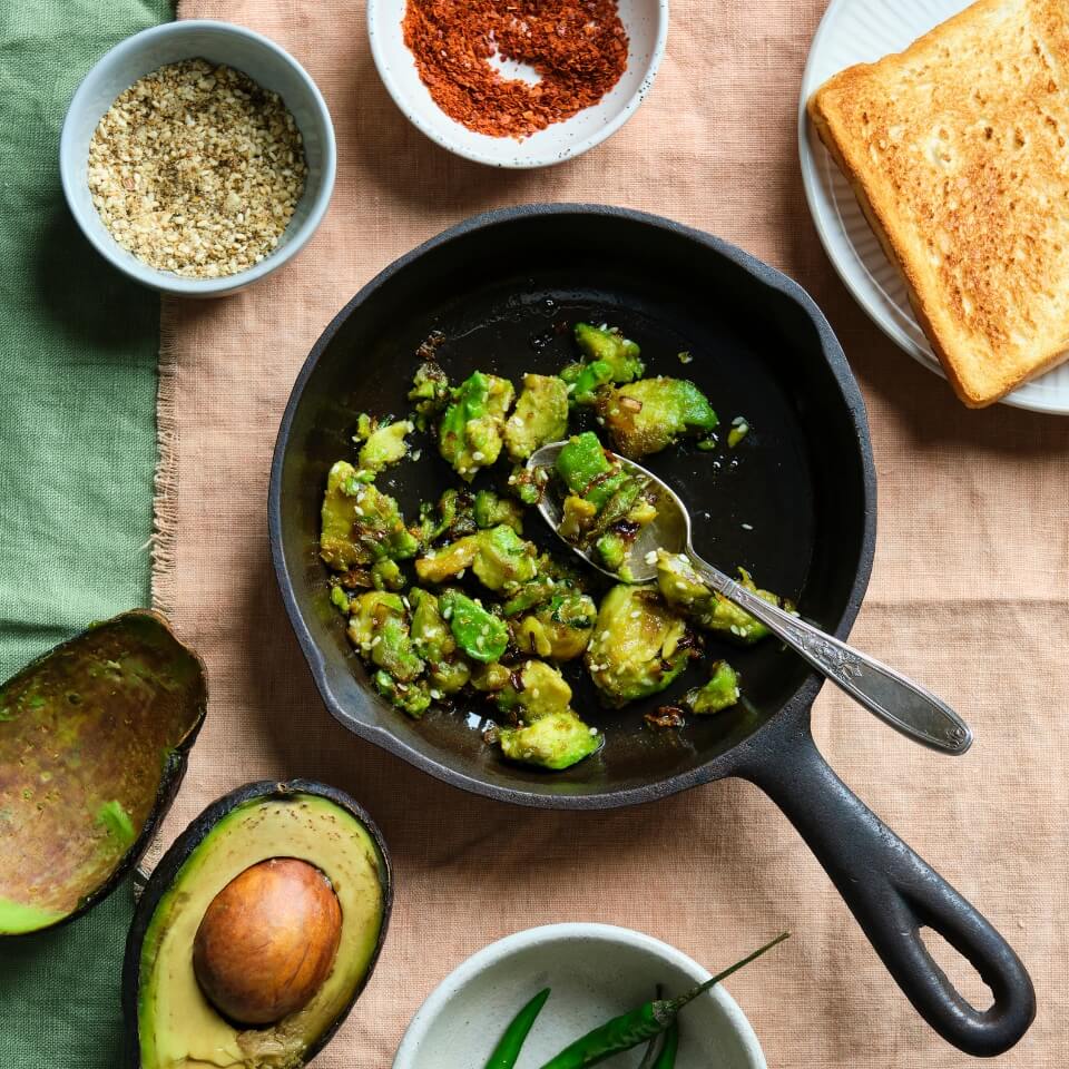 A skillet with avocado and toast next to it