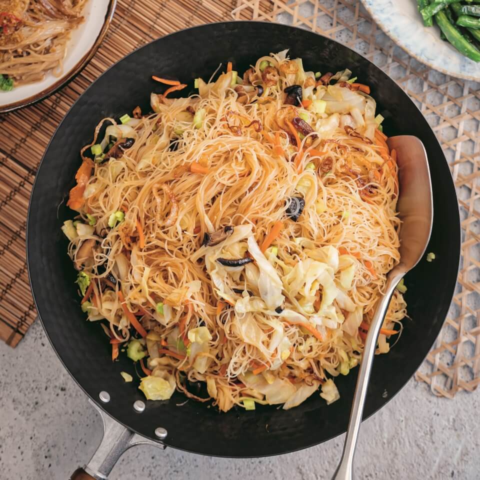 A stir-fry dish with noodles and a serving spoon