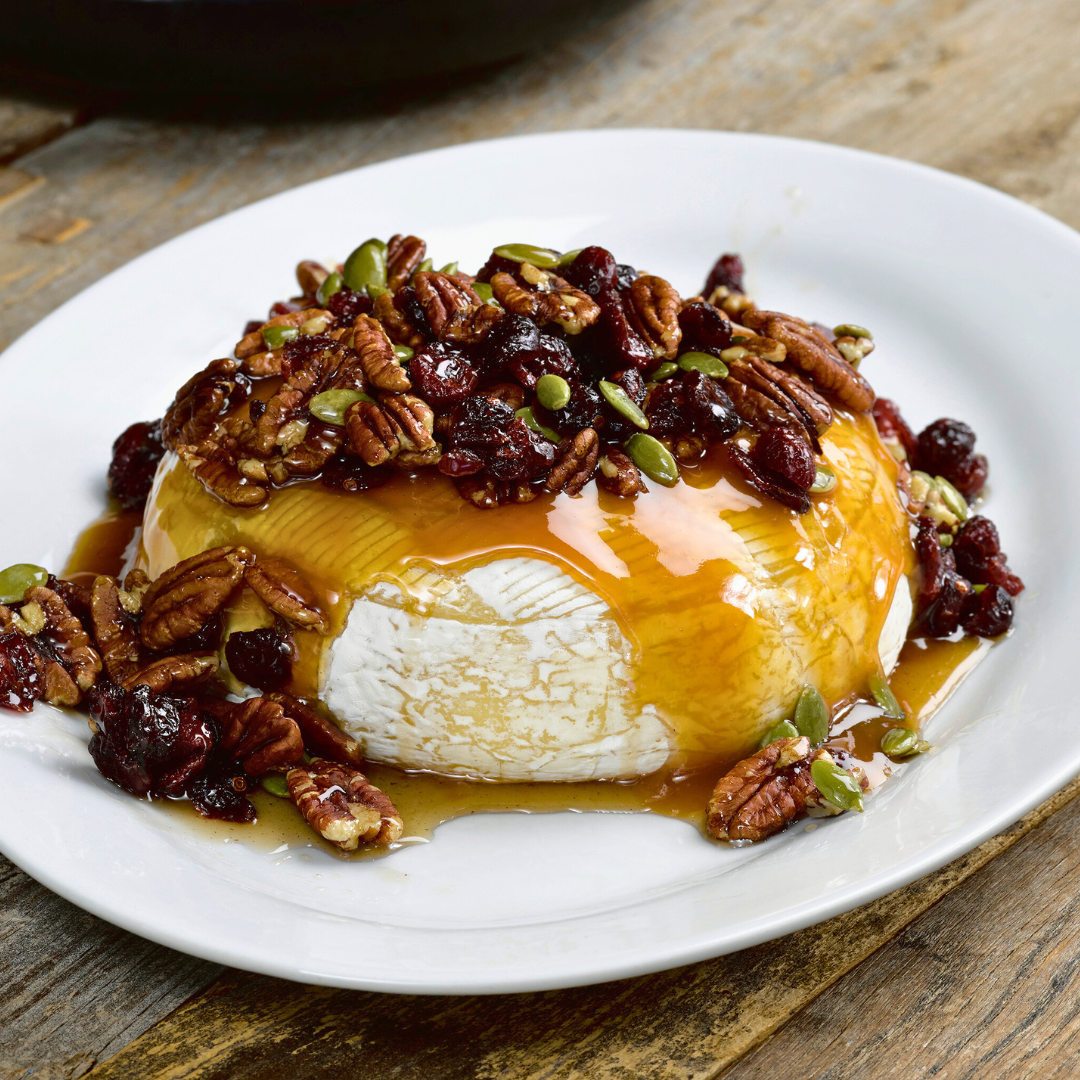 Baked brie topped with dried cranberries, pecans and maple syrup