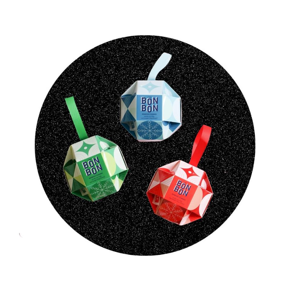 Three cardboard holiday ornaments inside a black sparkly circle