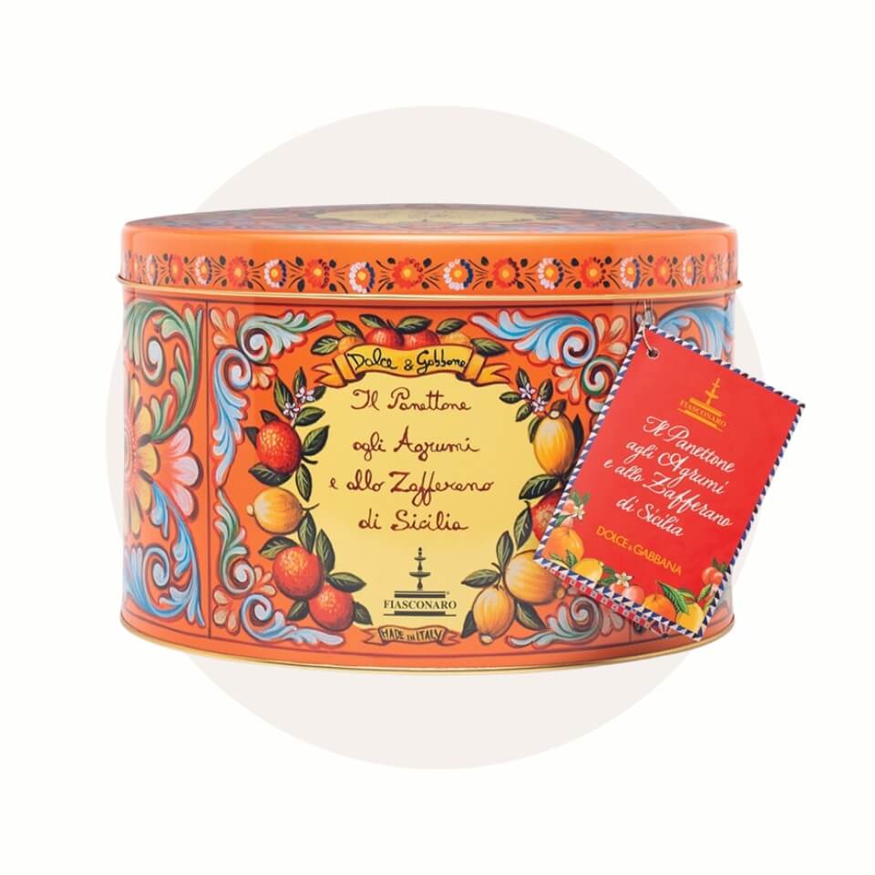 A panettone in a orange tin over a cream-coloured circle