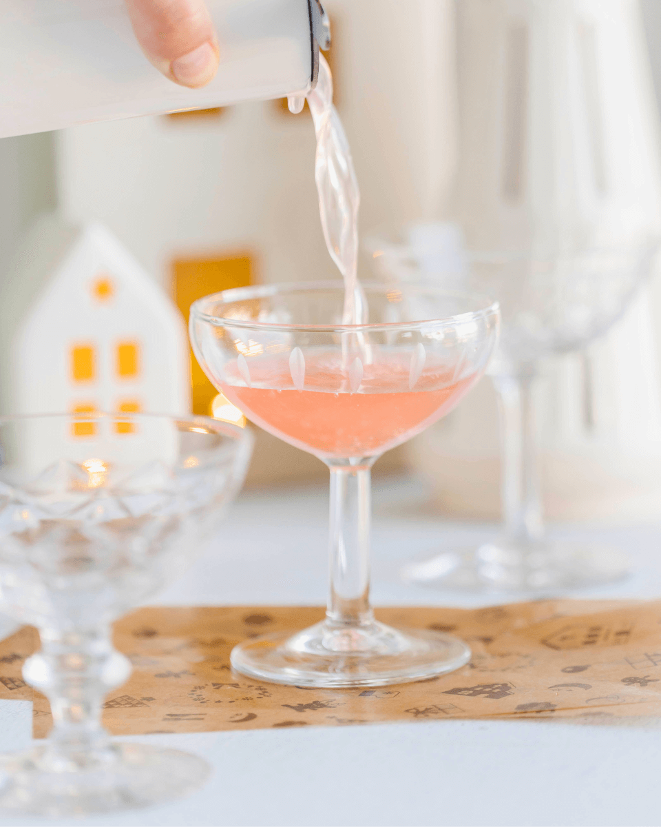 pink cocktail next to bottles