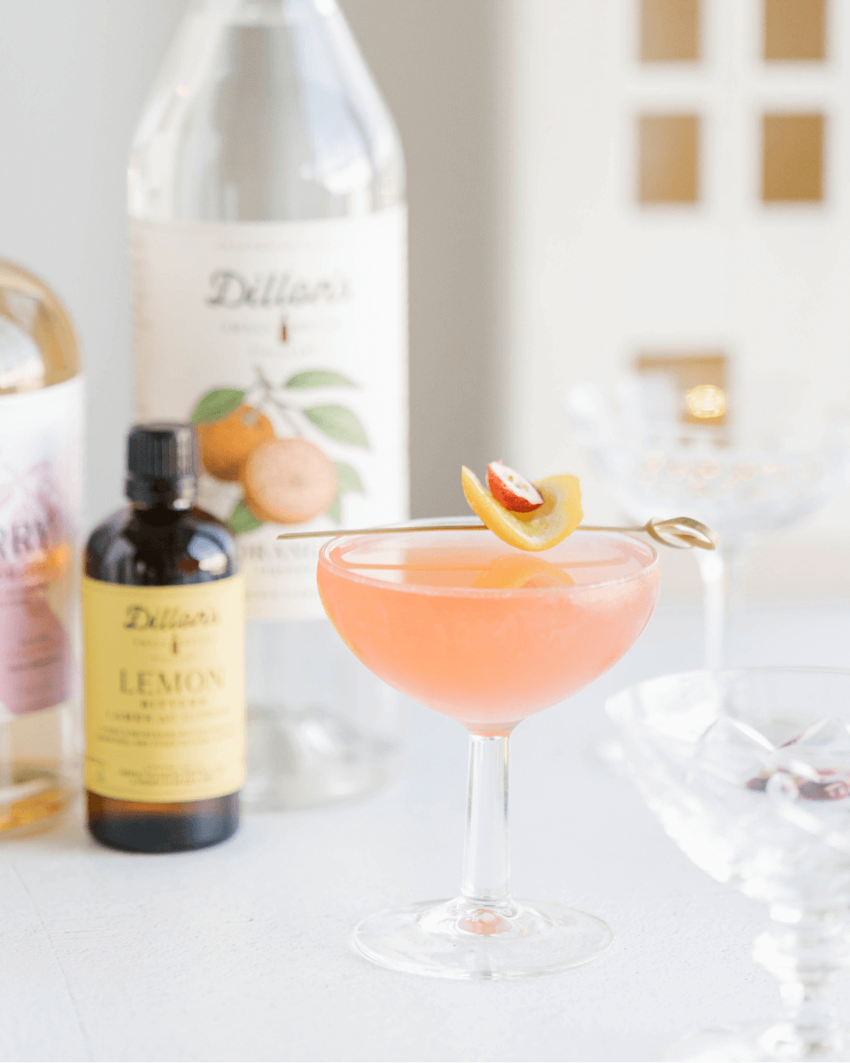 pink cocktail next to bottles