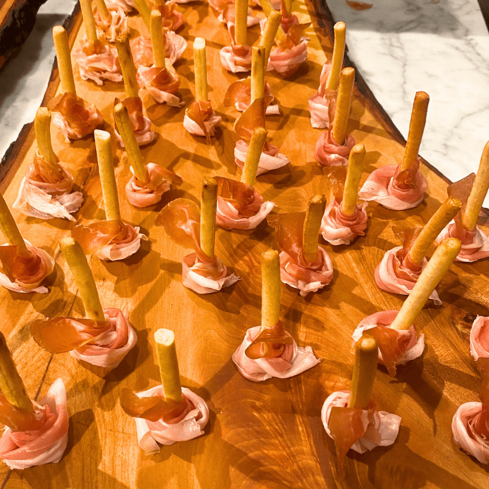 prosciutto pieces wrapped around grissini on wooden board