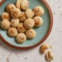 A turquoise-and-brown dish with crisp Italian amaretti cookies on a countertop and a broken one next to it