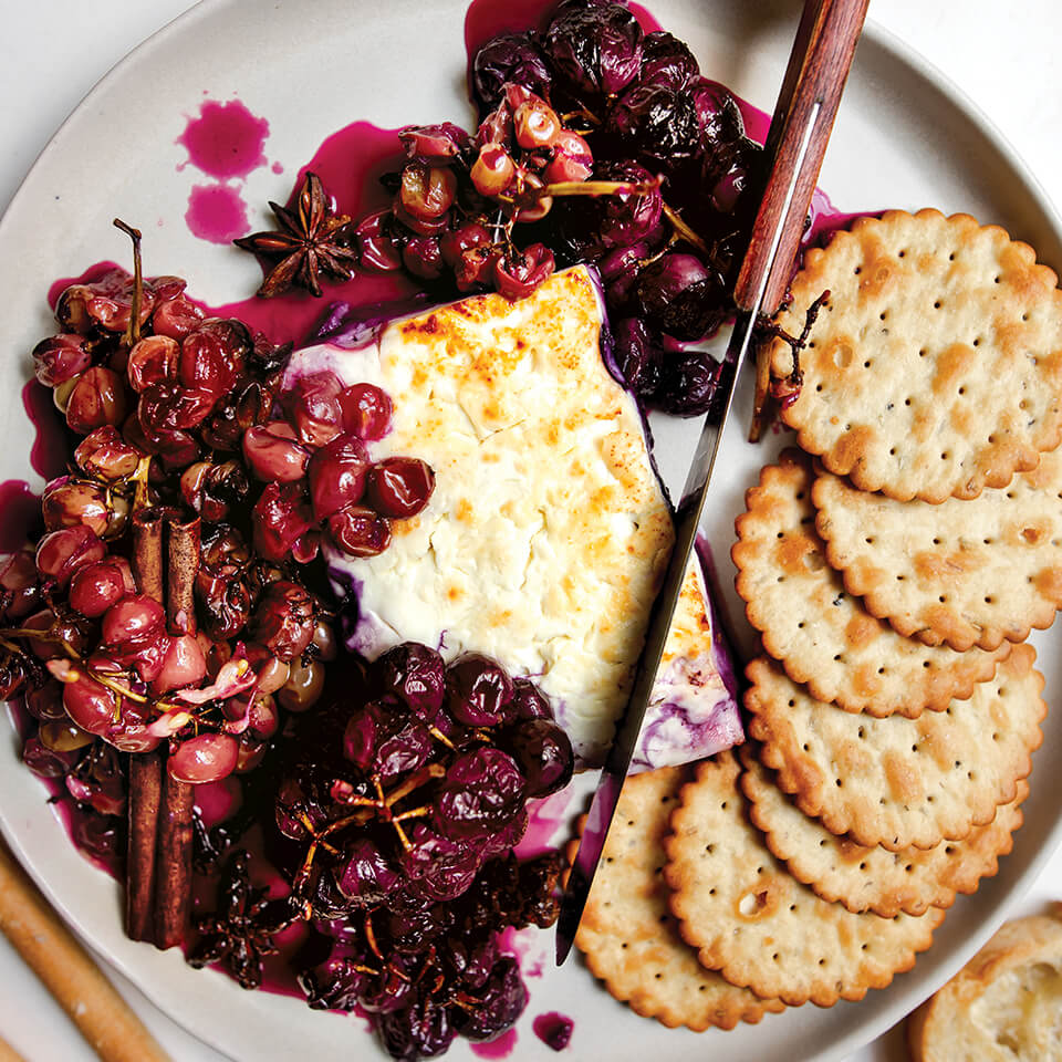 A dish with cheese, grapes and crackers