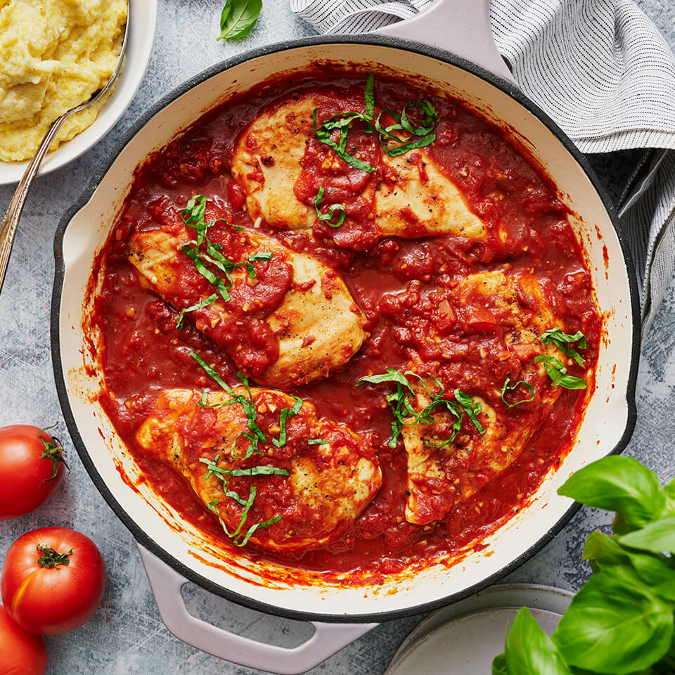 A skillet with chicken in tomato sauce