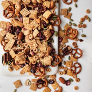 A recipe for Sweet and Salty Chex mix scattered on and spilling over a white marble board