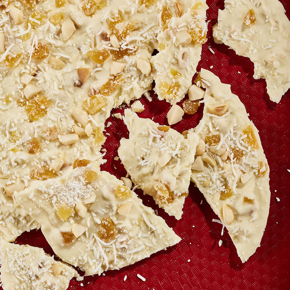 White chocolate bark on a red surface broken into pieces.