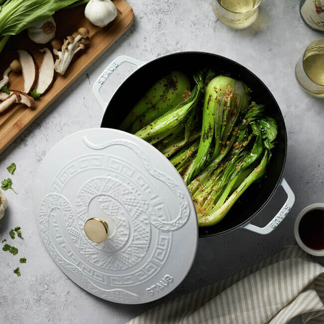 White braiser from staub with snake embossed lid and steamed box choy